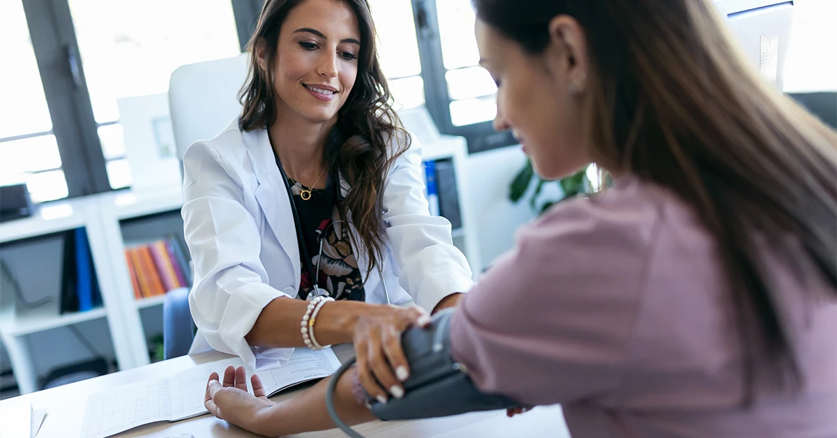 The doctor measures the woman's blood pressure.