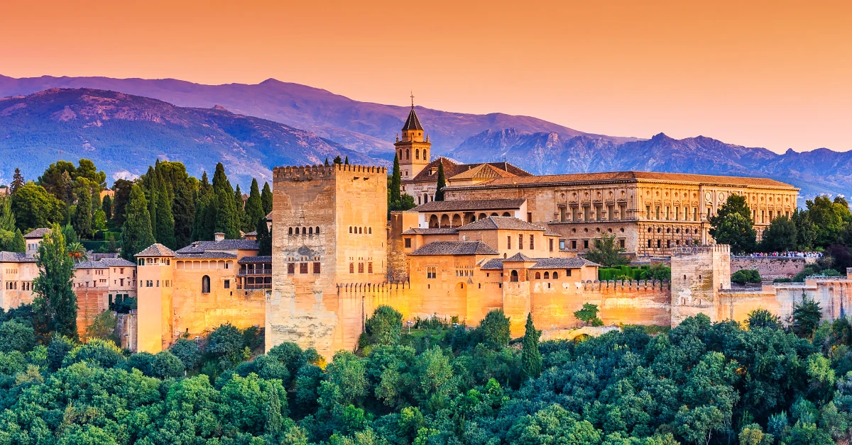 large building with trees and mountains in the background with the Alhambra