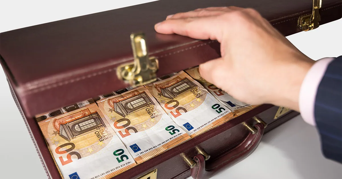 A man's hand opening a briefcase full of money