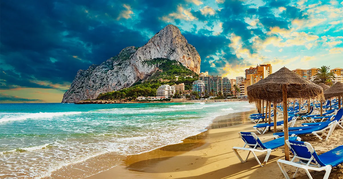 Beach with chairs and umbrellas and a mountain in the background