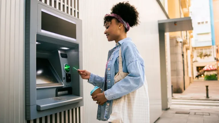 A young woman withdraws money from an ATM.