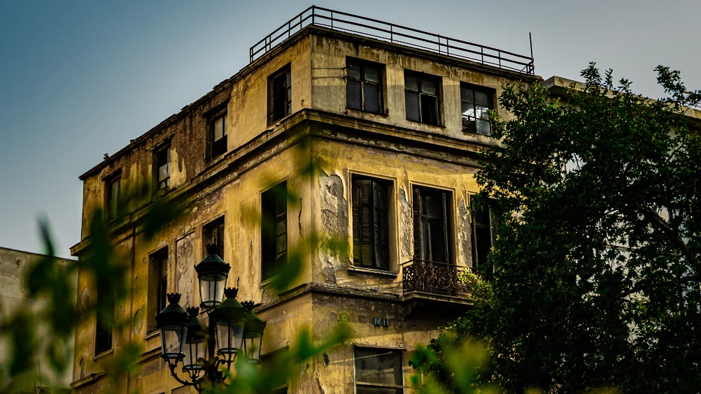 The photograph depicts a building in ruins, inhabited by squatters in Spain.