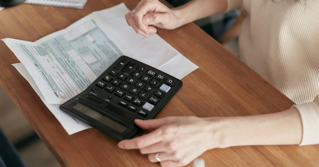 A woman calculates costs on a calculator.