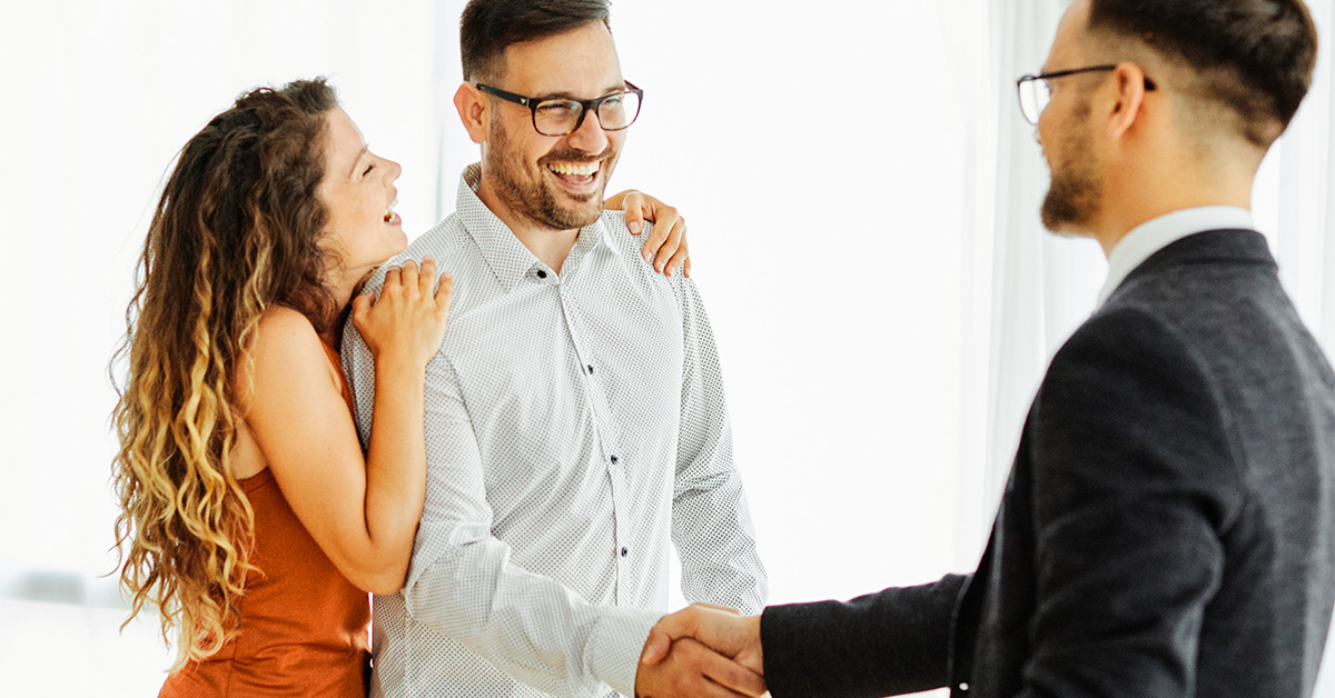 A man and a woman smile and shake hands with the agent.
